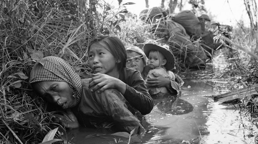 Hình ảnh Phụ nữ và trẻ em nấp trong kênh bùn với sự trợ giúp của binh sĩ Nam Việt Nam trong một trận giao chiến