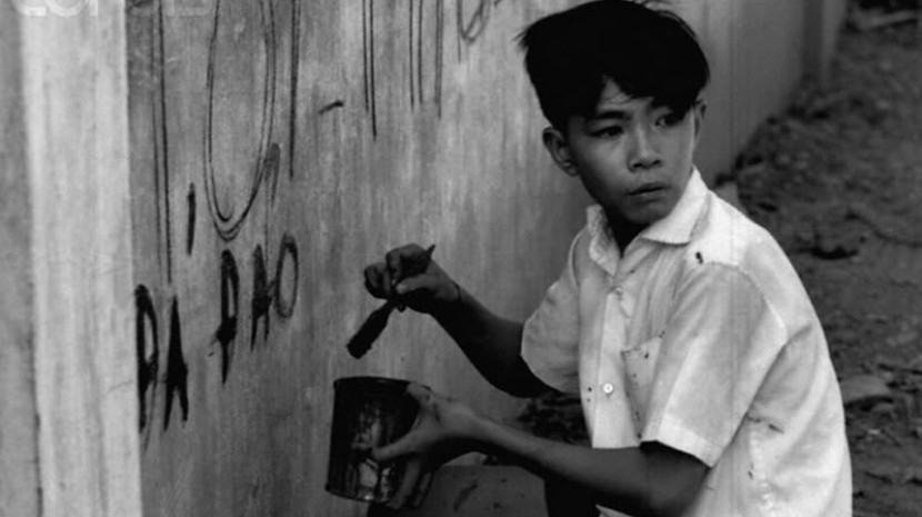 Một cậu bé vẽ một khẩu hiệu trên tường trong các cuộc biểu.tình